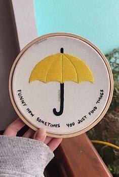 someone is holding up a yellow umbrella embroidered on a white hoop