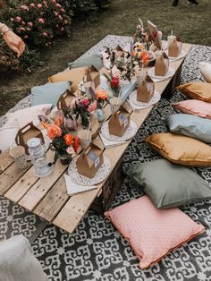 an outdoor table with pillows and flowers on it