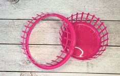 two pink plastic baskets sitting on top of a wooden floor next to each other,