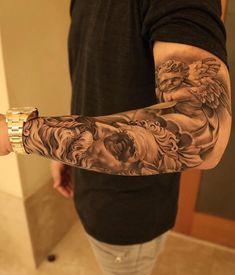 a man with a tattoo on his arm holding a glass in one hand and an angel on the other