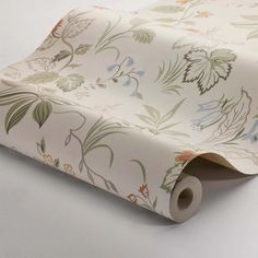 a roll of wrapping paper on top of a white table with flowers and leaves printed on it