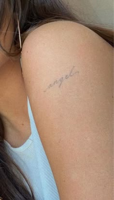 a close up of a person with a tattoo on her arm and the word angel written in cursive writing