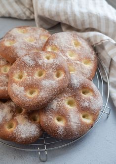 powdered sugar covered donuts on a wire rack