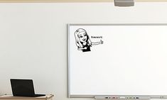 a whiteboard with a drawing of a woman pointing to the right and an open laptop on the left