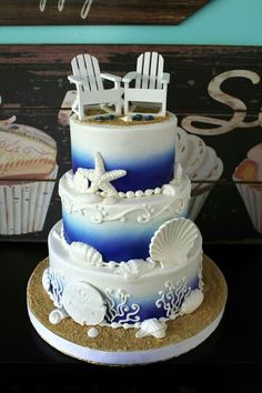 a three tiered cake with white and blue frosting on the top, decorated with beach chairs