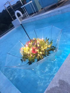 an umbrella that has some lights on it in the middle of a pool with water