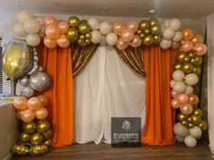 an orange and gold balloon arch with balloons