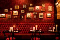 a restaurant with red upholstered booths and pictures on the wall, candles lit in front of them