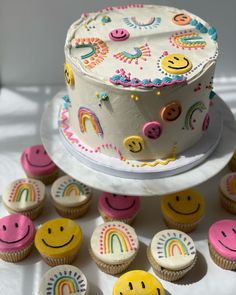 a white cake sitting on top of a table next to cupcakes