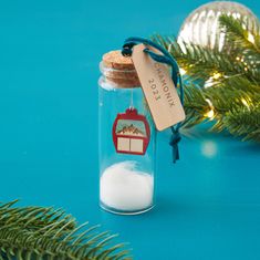 a glass jar filled with white powder next to a christmas ornament on a blue surface