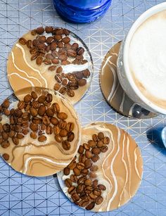 three desserts with coffee beans on them sitting on a table next to a cup of cappuccino