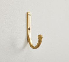 a gold coat hook on a white wall