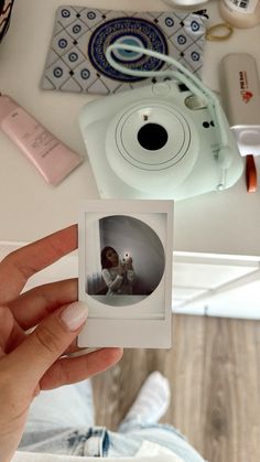 a person holding up a polaroid in front of a camera