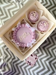 three cupcakes in a box with pink frosting