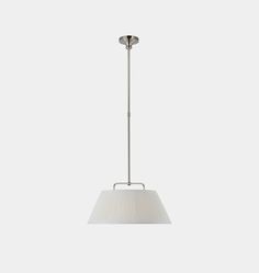 a light fixture with a white shade hanging from it's side on a gray background