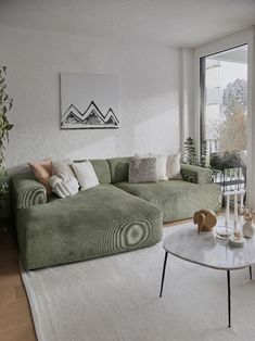 a living room filled with furniture next to a large window and a white rug on the floor