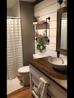 a white toilet sitting next to a wooden counter top in a bathroom under a mirror