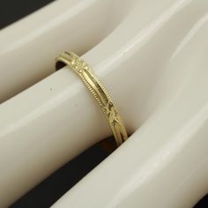 a gold wedding band with intricate designs on it