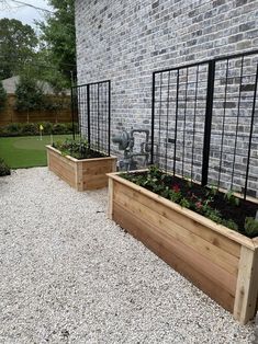 two wooden planters sitting next to each other in front of a brick wall and fence