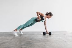 a woman is doing push ups with dumbbells