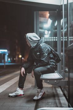 a person sitting on a bench in front of a bus stop with their back to the camera