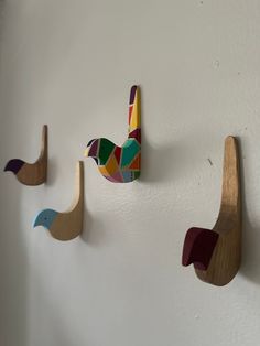 three wooden birds are hanging on the wall next to each other and one bird is painted multicolored