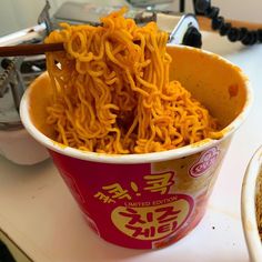 a bowl filled with noodles and chopsticks on top of a counter next to a sink