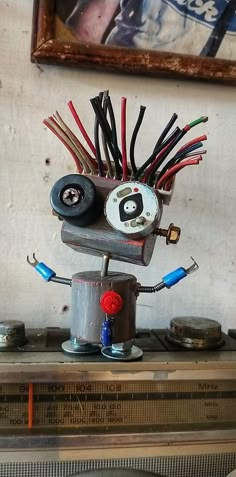 a robot made out of wires sitting on top of a table next to a painting