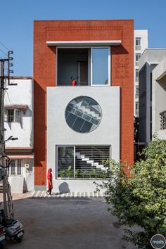 a person walking in front of a building with a large circular window on the side