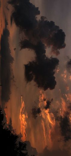 the sky is filled with dark clouds as the sun sets in the distance behind it