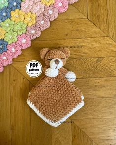 a crocheted teddy bear is laying on the floor next to a colorful rug