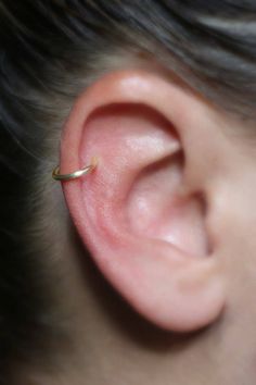 a close up of a person's ear with a tiny ring on it