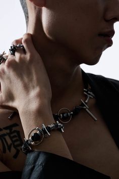 a man with tattoos on his arm wearing a black shirt and holding onto a silver bracelet