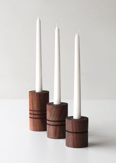 three white candles in wooden holders on a table