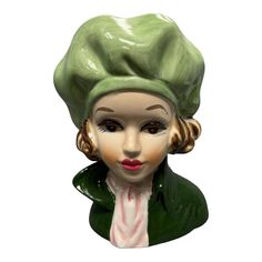 a ceramic busturine of a woman wearing a green hat