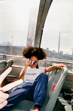 a woman sitting in the back of a bus talking on a cell phone while holding her hand up to her face