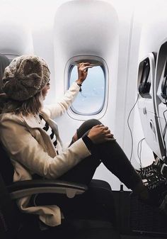 a woman sitting in an airplane looking out the window