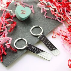 two key chains sitting on top of a table next to confetti and a box