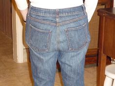 a man standing in the bathroom with his back to the camera, wearing jeans and a white t - shirt