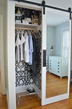 an open closet with clothes hanging on the wall and a mirror in front of it