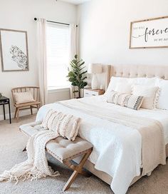 a bedroom with white bedding, pillows and blankets on the floor next to a window