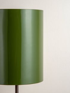 a green lamp on a table next to a white wall