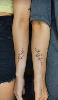 two people with tattoos on their arms holding each other's hands and one has a flower tattoo on her left arm