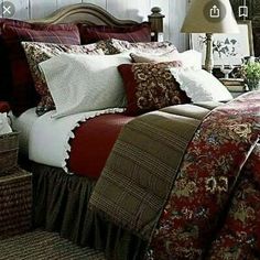 a bed with red and white comforter in a room next to a lamp on a table