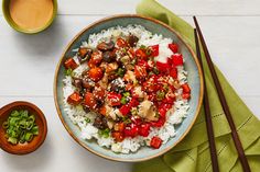 a bowl filled with rice, meat and vegetables next to chopsticks on a table