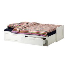 a bed with two drawers underneath it and a colorful blanket on top of the bed