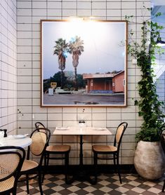 an empty restaurant with tables and chairs in front of a large painting on the wall