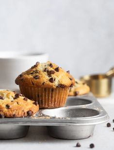 two muffins sitting on top of a metal tray next to a white cup