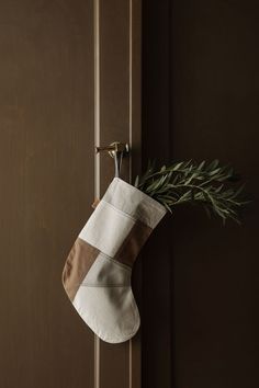 a stocking hanging on a door handle with a twig sticking out of it