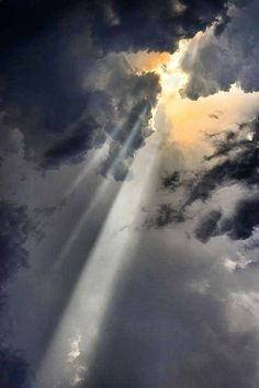 the sun is shining through dark clouds with light coming from it's beams in the sky